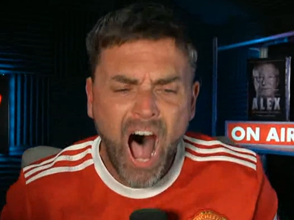Adam Stott in his Manchester united shirt yelling passionately in his studio setting.