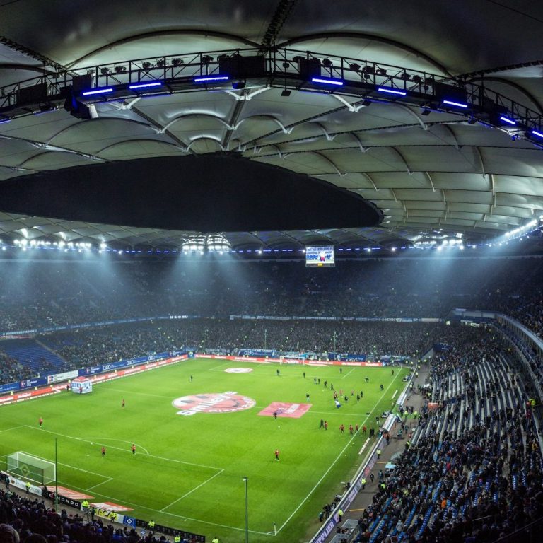 A large stadium filled with spectators, featuring a football match in progress.